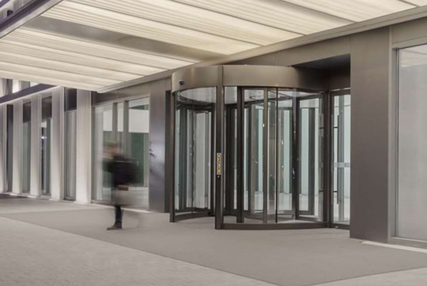 How do motion sensors work in automatic glass doors, and what are the key considerations for their placement and sensitivity settings?